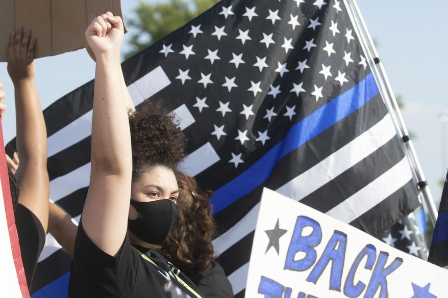 A Black Lives Matter supporter raises her fist in solidarity amid a crowd of "Back the Blue" supporters in Topeka, Kan., Aug. 25., 2020. Some advocates in Topeka see long-standing tensions between the police and the city's 125,000 residents, particularly minorities. But advocates of change have been met by vocal support for the police. (Evert Nelson/The Topeka Capital-Journal via AP)