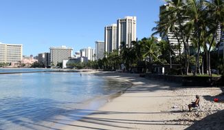 A man sits on a nearly empty Waikiki Beach in Honolulu, Friday, Oct. 2, 2020. After a summer marked by a surge of coronavirus cases in Hawaii, officials plan to reboot the tourism based economy later this month despite concerns about the state&#39;s pre-travel testing program. (AP Photo/Caleb Jones)
