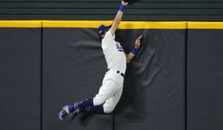 Los Angeles Dodgers&#39; Cody Bellinger slams into the outfield wall and makes the catch as he robs San Diego Padres&#39; Fernando Tatis Jr. of a home run on a deep drive during the seventh inning in Game 2 of a baseball National League Division Series Wednesday, Oct. 7, 2020, in Arlington, Texas. (AP Photo/Sue Ogrocki)
