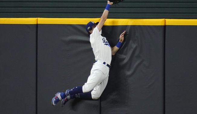 Los Angeles Dodgers&#x27; Cody Bellinger slams into the outfield wall and makes the catch as he robs San Diego Padres&#x27; Fernando Tatis Jr. of a home run on a deep drive during the seventh inning in Game 2 of a baseball National League Division Series Wednesday, Oct. 7, 2020, in Arlington, Texas. (AP Photo/Sue Ogrocki)
