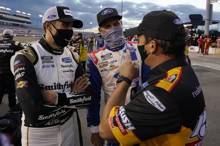 Aric Almirola, left, and Clint Bowyer, center, talks to a crew member prior to the start of a NASCAR Cup Series auto race Saturday, Sept. 12, 2020, in Richmond, Va. (AP Photo/Steve Helber)