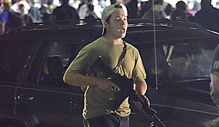 In this Tuesday, Aug. 25, 2020, file photo, Kyle Rittenhouse carries a weapon as he walks along Sheridan Road in Kenosha, Wis., during a night of unrest following the weekend police shooting of Jacob Blake. (Adam Rogan/The Journal Times via AP, File)