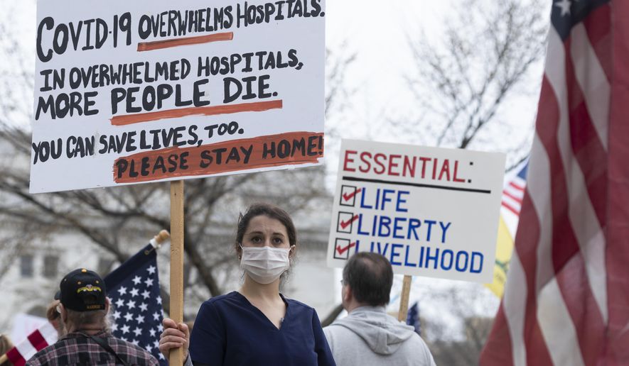 FILE - In this April 24, 202, file photo, a nurse demonstrating in favor of business closures is surrounded by demonstrators against Gov. Tony Evers' restrictions on daily life due to the coronavirus pandemic at the Capitol in Madison, Wis. Doctors and nurses treating those sick and dying from the coronavirus said politics around social distancing and the lethality of the virus are complicating treatment efforts. (Mark Hoffman/Milwaukee Journal-Sentinel via AP, File)