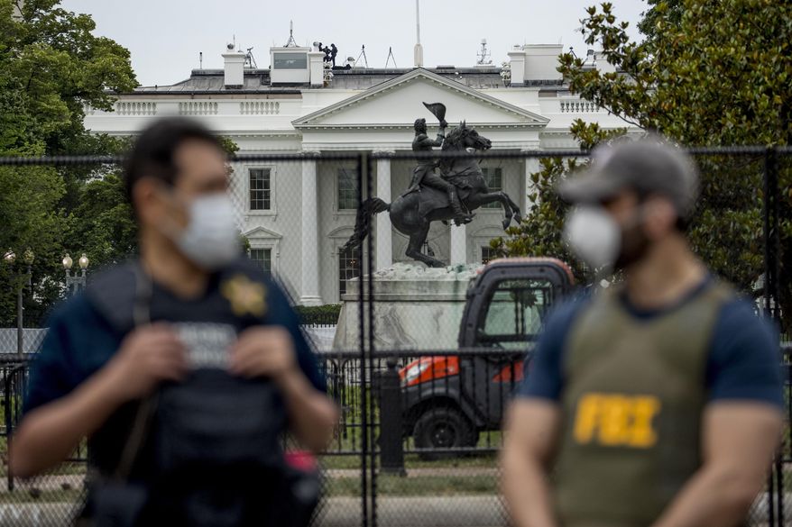 In this June 2, 2020, file photo, the White House is visible behind a large security fence as uniformed Secret Service and FBI agents stand on the street in front of Lafayette Park in the morning hours in Washington. Federal and state law enforcement officials have begun expanded preparations for the possibility of widespread unrest at the polls on Election Day, a response to extraordinarily high tensions among voters and anxieties about safety stoked in part by President Donald Trump. (AP Photo/Andrew Harnik, File)