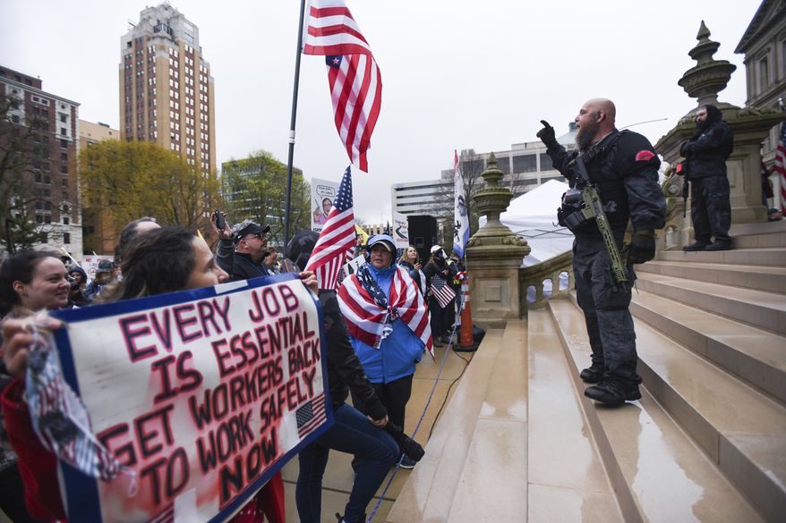 In this April 30, 2020 file photo, protesters rally to denounce Gov. Gretchen Whitmer's stay-home order and business restrictions due to COVID-19, at the state Capitol in Lansing, Mich. Among the protesters who rallied at the Michigan Capitol against Gov. Gretchen Whitmers coronavirus lockdown last spring were armed men now facing charges in a stunning plot to kidnap her. The development has sparked renewed calls for a gun ban in the building and scrutiny of the rallies as potential recruitment events. (Matthew Dae Smith/Lansing State Journal via AP, File)/Lansing State Journal via AP)