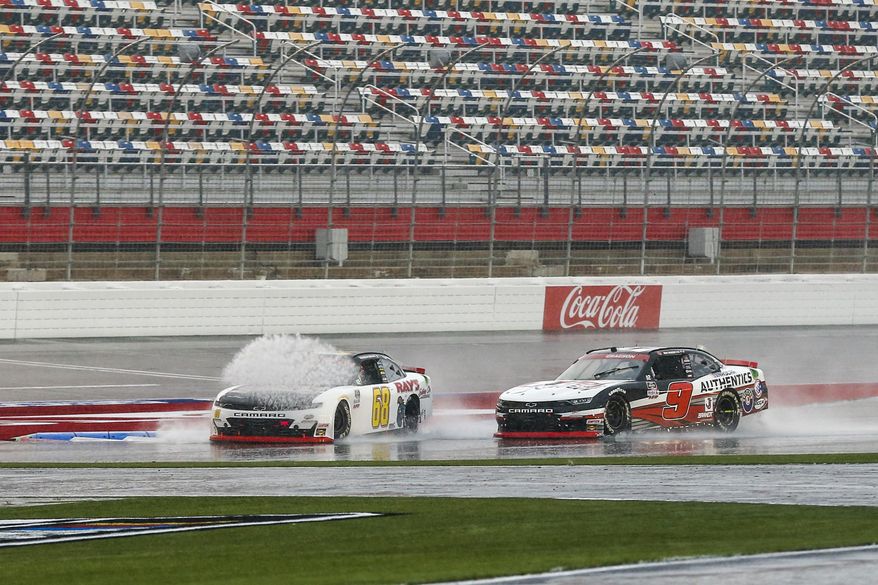 Brandon Brown (68) hits a puddle in front of Noah Gragson (9) during a NASCAR Xfinity Series auto race at Charlotte Motor Speedway in Concord, N.C., Saturday, Oct. 10, 2020. (AP Photo/Nell Redmond)