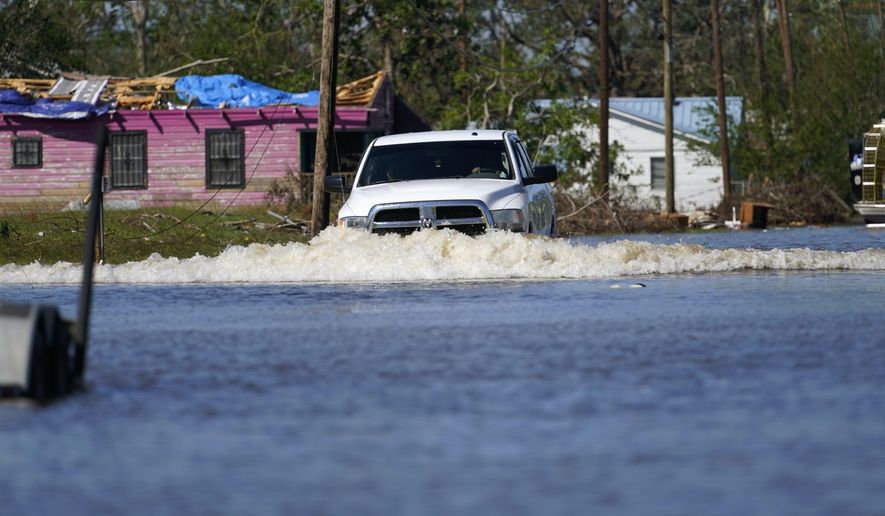 A truck drives through a flooded street in Lake Charles, La., Saturday, Oct. 10, 2020, past a home with damage from Hurricane Laura, after Hurricane Delta moved through on Friday. (AP Photo/Gerald Herbert)