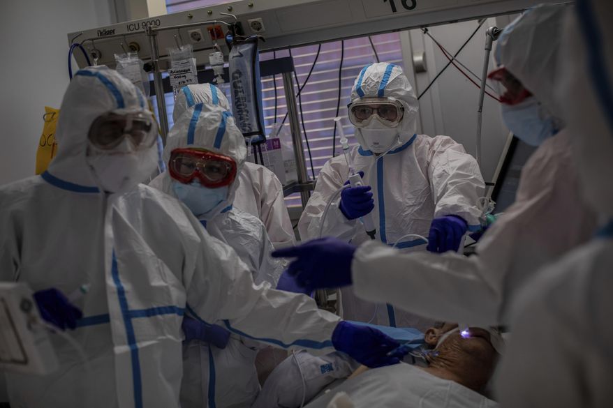 FILE - In this Oct. 9, 2020, file photo, a medical team treats a patient infected with COVID-19 in one of the intensive care units (ICU) at the Severo Ochoa hospital in Leganes, outskirts of Madrid, Spain. Europe’s second wave of coronavirus infections has struck well before flu season even started. Intensive care wards are filling up again and bars are shutting down. (AP Photo/Bernat Armangue, File)
