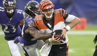 Baltimore Ravens cornerback Marcus Peters, left, forces a fumble on Cincinnati Bengals quarterback Joe Burrow during the second half of an NFL football game, Sunday, Oct. 11, 2020, in Baltimore. The ball bounced out of bounds and the Bengals retained possession. (AP Photo/Nick Wass)