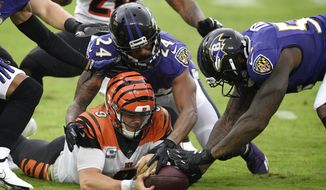 Cincinnati Bengals quarterback Joe Burrow, bottom left, tries to retrieve his fumble as Baltimore Ravens cornerback Marcus Peters (24) and defensive end Jihad Ward (53) challenge him for the recovery during the second half of an NFL football game, Sunday, Oct. 11, 2020, in Baltimore. The ball bounced out of bounds and the Bengals retained possession. (AP Photo/Nick Wass)