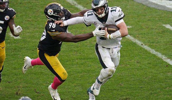Philadelphia Eagles quarterback Carson Wentz (11) scrambles out of the pocket under pressure by Philadelphia Eagles defensive tackle Hassan Ridgeway (98) during the second half of an NFL football game, Sunday, Oct. 11, 2020, in Pittsburgh. (AP Photo/Keith Srakocic)