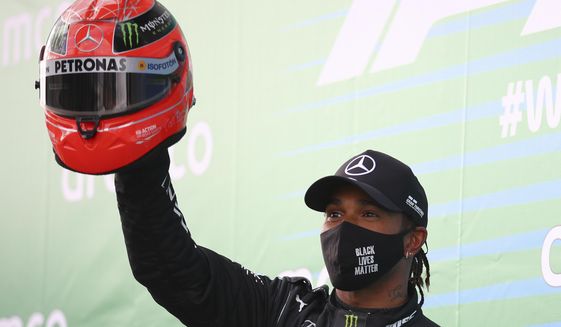 Mercedes driver Lewis Hamilton of Britain shows a helmet of former German driver Michael Schumacher after he wins the Eifel Formula One Grand Prix at the Nuerburgring racetrack in Nuerburg, Germany, Sunday, Oct. 11, 2020. Hamilton gets the helmet as a gift from Michael Schumacher&#39;s son Mick because he equals Schumacher&#39;s record of 91 wins in the Formula One. (Bryn Lennon, Pool via AP)