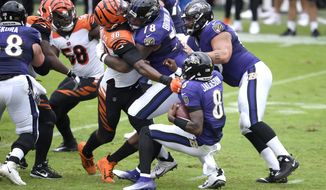 Cincinnati Bengals defensive end Carlos Dunlap (96) is able to sack Baltimore Ravens quarterback Lamar Jackson (8) in spite of being blocked by Ravens offensive tackle Orlando Brown (78) during the first half of an NFL football game, Sunday, Oct. 11, 2020, in Baltimore. (AP Photo/Nick Wass)