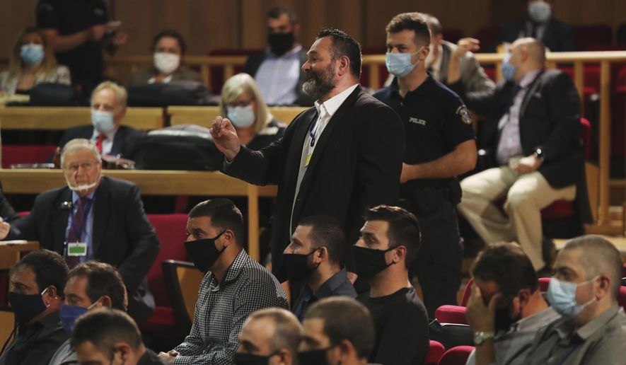 European Parliament member Ioannis Lagos, center, who had been found guilty along with others of leading a criminal organization, and face five to 15 years in prison, talks in a court, about his sentencing in Athens, Monday, Oct. 12, 2020. An Athens court has extended to Monday a sentencing hearing for leading members and associates of Greece's far-right Golden Dawn convicted earlier this week of multiple crimes. (AP Photo/Petros Giannakouris)