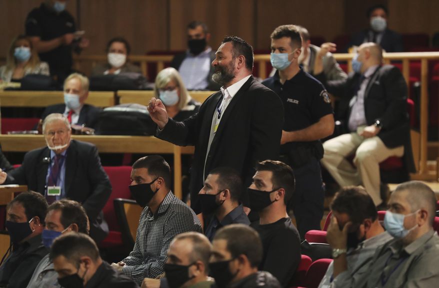 European Parliament member Ioannis Lagos, center, who had been found guilty along with others of leading a criminal organization, and face five to 15 years in prison, talks in a court, about his sentencing in Athens, Monday, Oct. 12, 2020. An Athens court has extended to Monday a sentencing hearing for leading members and associates of Greece's far-right Golden Dawn convicted earlier this week of multiple crimes. (AP Photo/Petros Giannakouris)