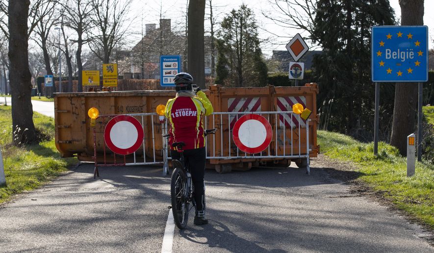 FILE - In this Monday, March 23, 2020 file photo, a cyclist takes images of a barricaded backroad used by locals on the Netherlands border with Belgium between Chaam, southern Netherlands, and Meerle, Northern Belgium. European Union countries are set to adopt a common traffic light system to coordinate traveling across the 27-nation bloc, but a return to a full freedom of movement in the midst of the COVID-19 pandemic remains far from reach. (AP Photo/Peter Dejong, File)