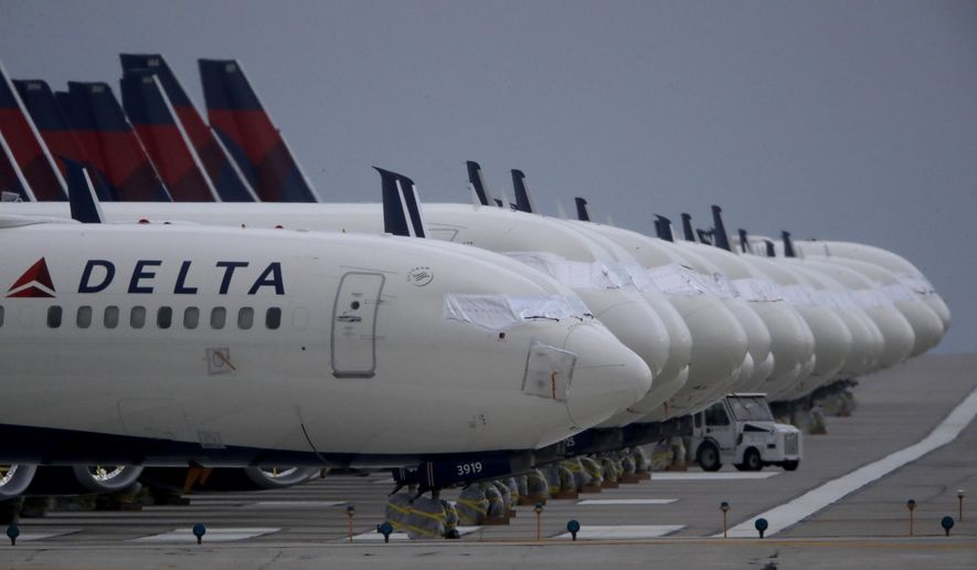FILE - In this May 14, 2020 file photo, several dozen mothballed Delta Air Lines jets are parked on a closed runway at Kansas City International Airport  in Kansas City, Mo. Delta Air Lines is the first carrier to report financial results for the third quarter, and the numbers are grim. Delta said Tuesday, Oct. 13 that it lost nearly $6.9 billion as travel remain depressed over the normally peak vacation season because of the pandemic.  (AP Photo/Charlie Riedel, File)