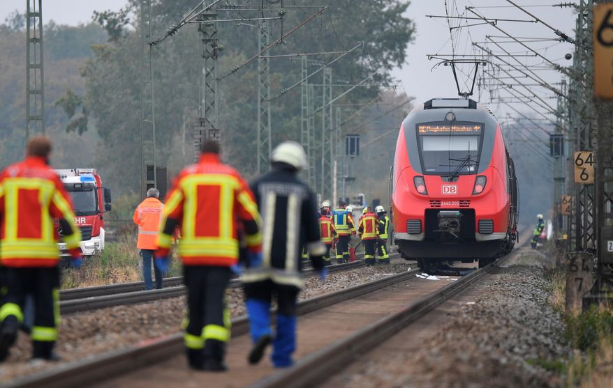 Rescue workers are on duty at the scene of a train accident in Bruckberg, Germany, Tuesday, Oct. 13, 2020. Two teenager brothers were hit and killed by a train in Bavaria on Tuesday as they apparently ran across the tracks in an attempt to make their own connection, police said. (Matthias Balk/dpa via AP)