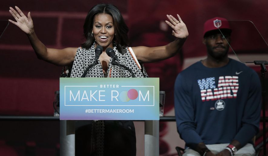 FILE - In this Oct. 21, 2015, file photo, former first lady Michelle Obama speaks at the University of Akron as NBA star LeBron James listens in rear, in Akron, Ohio. A voter initiative led by Michelle Obama is partnering with a similar group founded by NBA star LeBron James and other prominent Black athletes and entertainers to generate excitement about voting early for the Nov. 3 election. (AP Photo/Tony Dejak, File)
