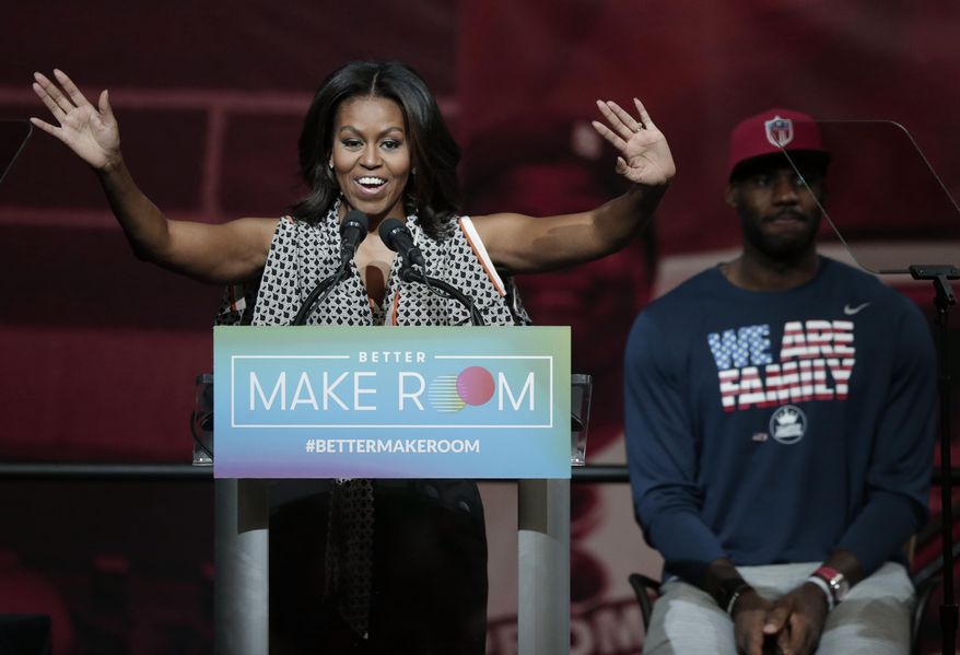 FILE - In this Oct. 21, 2015, file photo, former first lady Michelle Obama speaks at the University of Akron as NBA star LeBron James listens in rear, in Akron, Ohio. A voter initiative led by Michelle Obama is partnering with a similar group founded by NBA star LeBron James and other prominent Black athletes and entertainers to generate excitement about voting early for the Nov. 3 election. (AP Photo/Tony Dejak, File)