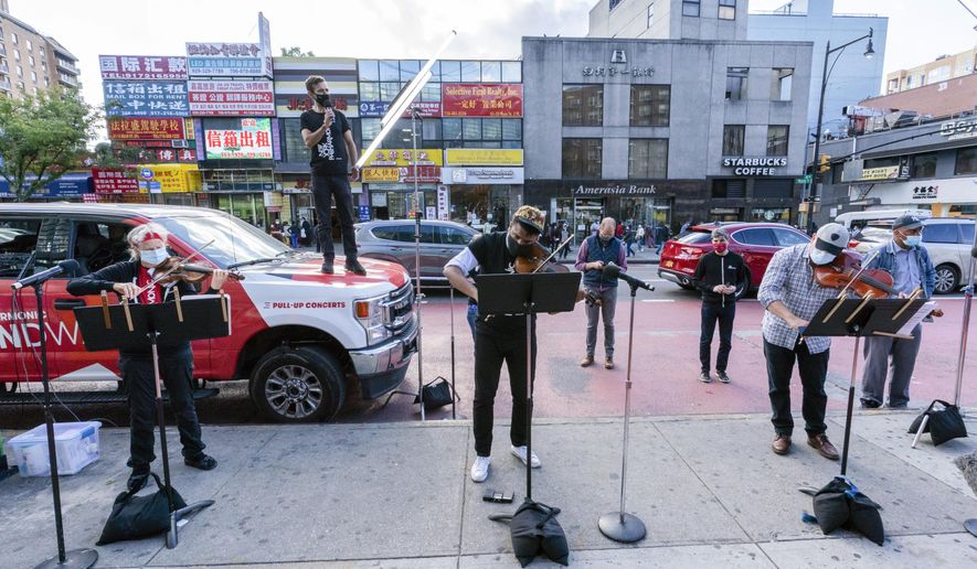 Members of the NY Phil Bandwagon, from left, violinist Fiona Simon, countertenor and producer Anthony Roth Costanzo, violinist Curtis Stewart and viola player Robert Rinehart perform in the Flushing neighborhood of the Queens borough of New York, Friday, Oct. 2, 2020. The NY Phil Bandwagon travels to three unannounced locations around New York City, Friday through Sunday, for an impromptu pullup chamber music concert as part of the New York Philharmonic's Fall 2020 activities. (AP Photo/Mary Altaffer)