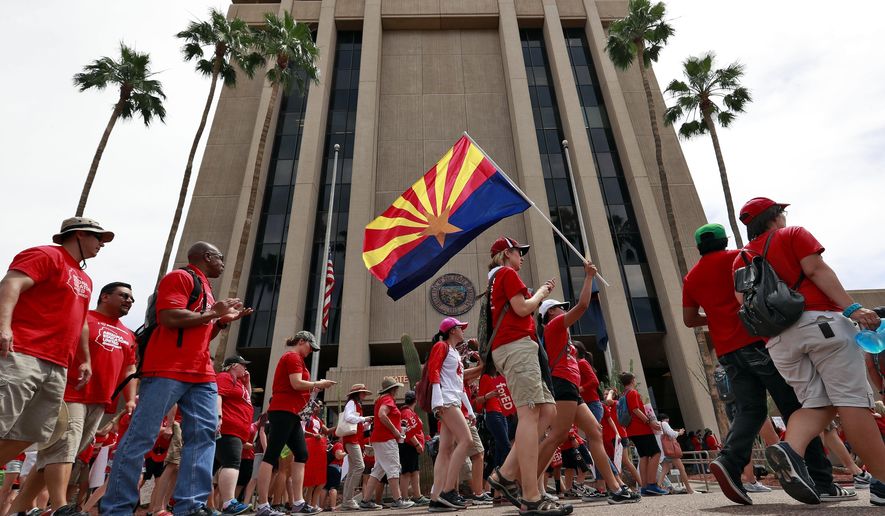 FILE - In this April 30, 2018, file photo, teachers rally outside of Arizona Gov. Doug Ducey&#x27;s Executive Tower in Phoenix on their third day of walkouts. Public schools in Arizona that have weathered a decade of funding cuts with only partial restoration could see a big infusion of cash if a ballot measure backed by teachers and advocacy groups passes in November, but opponents say Proposition 208 will hurt the economy and only bring partial relief. (AP Photo/Matt York, File)