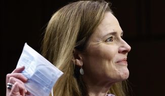 Supreme Court nominee Amy Coney Barrett holds a face mask up as she testifies during the third day of her confirmation hearings before the Senate Judiciary Committee on Capitol Hill in Washington, Wednesday, Oct. 14, 2020. (Photo by Samuel Corum/Getty Images)