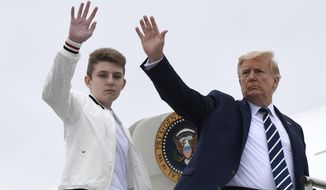 FILE - In this Aug. 16, 2020 file photo, President Donald Trump, right, and his son Barron Trump wave from the top of the steps to Air Force One at Morristown Municipal Airport in Morristown, N.J.  (AP Photo/Susan Walsh)