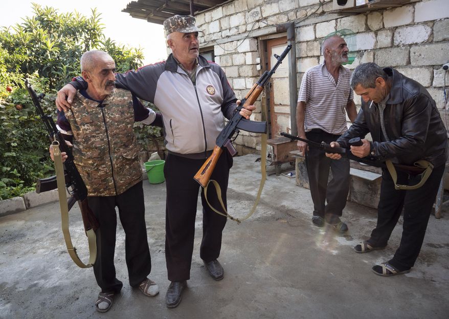 Local residents hold Kalashnikov guns that they received from a recruitment office in the town of Martuni, the separatist region of Nagorno-Karabakh, Wednesday, Oct. 14, 2020. The conflict between Armenia and Azerbaijan is escalating, with both sides exchanging accusations and claims of attacks over the separatist territory of Nagorno-Karabakh. Heavy fighting is in a third week despite a cease-fire deal. (AP Photo)