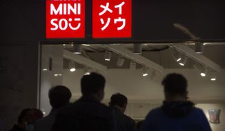 People walk past a Miniso shop at a shopping mall in Beijing, Thursday, Oct. 15, 2020.  Miniso, a Chinese discount retailer known for its fashionable but affordable household products, is expected to raise up to $562 million in a U.S. initial public offering in New York. The Guangzhou-based retailer is the latest Chinese company to list in the U.S., amid tensions that have taken U.S.-China relations to their worst level in decades. (AP Photo/Mark Schiefelbein)