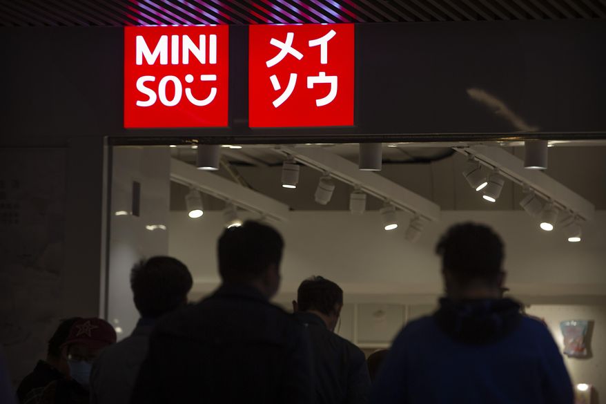 People walk past a Miniso shop at a shopping mall in Beijing, Thursday, Oct. 15, 2020.  Miniso, a Chinese discount retailer known for its fashionable but affordable household products, is expected to raise up to $562 million in a U.S. initial public offering in New York. The Guangzhou-based retailer is the latest Chinese company to list in the U.S., amid tensions that have taken U.S.-China relations to their worst level in decades. (AP Photo/Mark Schiefelbein)