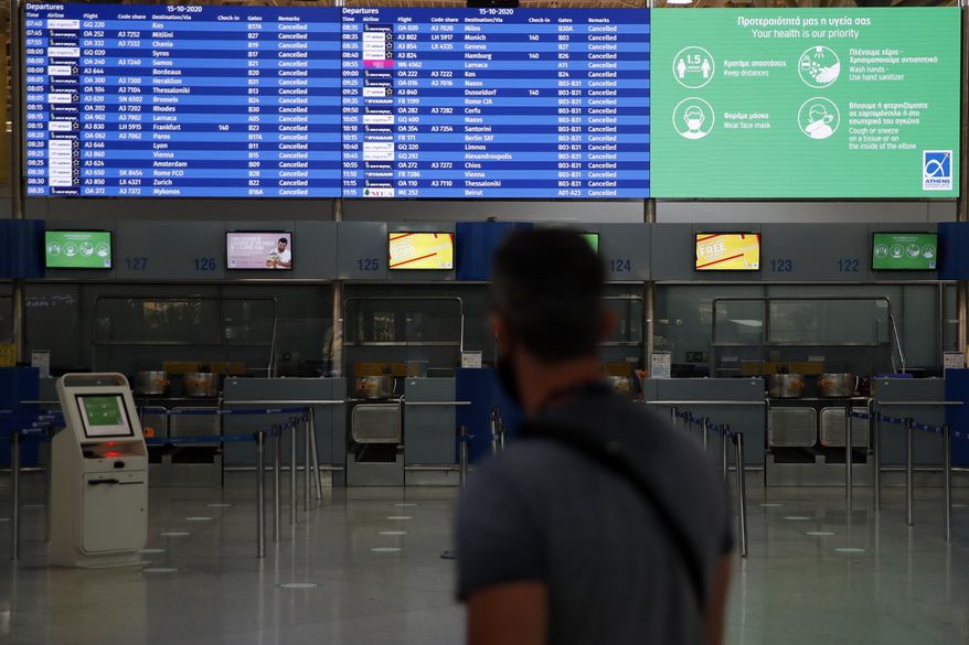 A board shows the cancelled flights as a man walks at the empty Eleftherios Venizelos International Airport during a 24-hour strike in public sector in Athens, Thursday, Oct. 15. 2020. Greece's air traffic electronic engineers and air traffic control personnel, participate in the 24-hour strike organised by civil servant union ADEDY demanding, among other things, better pay for health and education workers and the need for more recruitments of medical workers amidst the pandemic. (AP Photo/Thanassis Stavrakis)