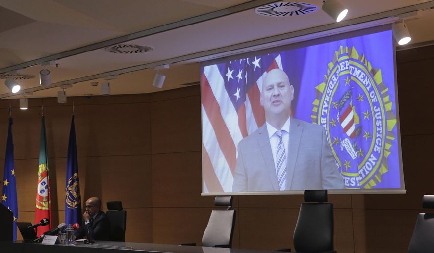 FBI Pittsburgh Special Agent Michael Christman speaks in a video presented by Portuguese police chief inspector Paulo Goncalves, at left, during a news conference at the police headquarters in Lisbon, Thursday, Oct. 15, 2020. European and American officials say that they have arrested 20 individuals for allegedly belonging to an international ring that laundered millions of euros stolen by cybercriminals in an international police operation led by Portuguese investigators and the F.B.I. (AP Photo/Armando Franca)