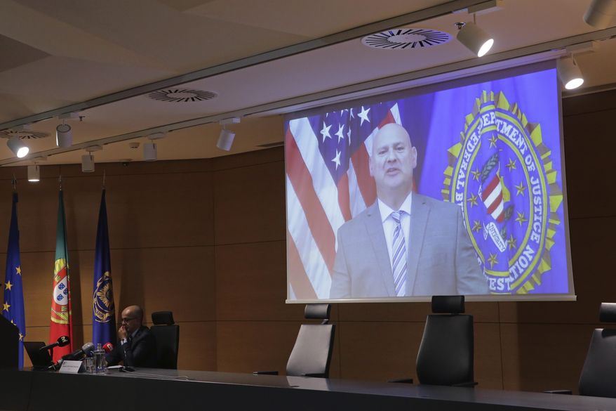 FBI Pittsburgh Special Agent Michael Christman speaks in a video presented by Portuguese police chief inspector Paulo Goncalves, at left, during a news conference at the police headquarters in Lisbon, Thursday, Oct. 15, 2020. European and American officials say that they have arrested 20 individuals for allegedly belonging to an international ring that laundered millions of euros stolen by cybercriminals in an international police operation led by Portuguese investigators and the F.B.I. (AP Photo/Armando Franca)