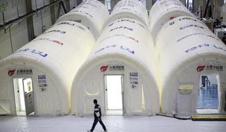 A man walks past temporary COVID-19 test processing labs set up inside inflatable tents in Qingdao in eastern China&#39;s Shandong Province, Wednesday, Oct. 14, 2020. China says it has carried out more than 4.2 million tests in the northern port city of Qingdao, with no new cases of coronavirus found among the almost 2 million sets of results received. (Chinatopix via AP)