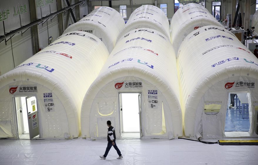 A man walks past temporary COVID-19 test processing labs set up inside inflatable tents in Qingdao in eastern China&#39;s Shandong Province, Wednesday, Oct. 14, 2020. China says it has carried out more than 4.2 million tests in the northern port city of Qingdao, with no new cases of coronavirus found among the almost 2 million sets of results received. (Chinatopix via AP)