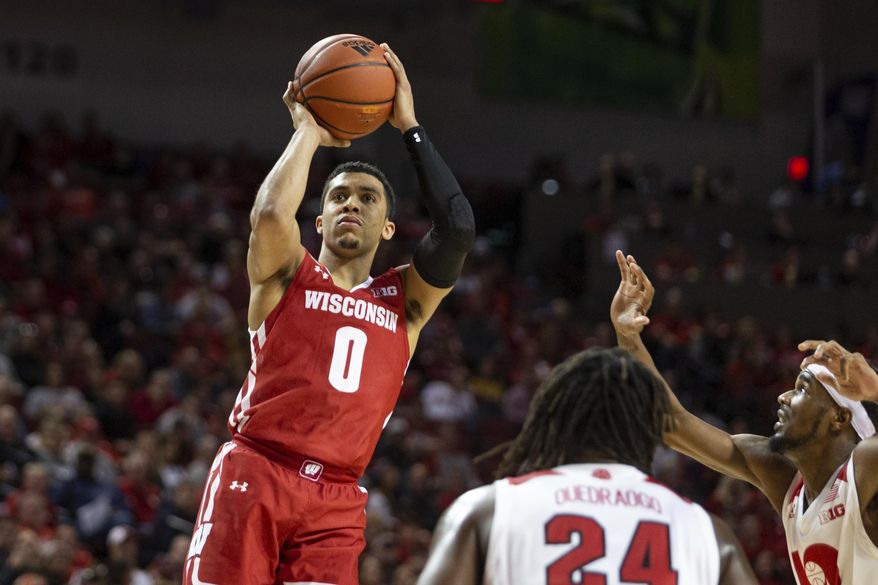 FILE - In this Feb. 15, 2020, file photo, Wisconsin guard D'Mitrik Trice (0) puts up a jump shot against Nebraska guard Dachon Burke Jr. (11) and Nebraska forward Yvan Ouedraogo (24) during the second half of an NCAA college basketball game in Lincoln, Neb. Wisconsin is trying not to think about its missed opportunity from last March as the Badgers seek to build on the momentum they established before the pandemic shut down the 2019-20 season prematurely. (AP Photo/John Peterson, File)
