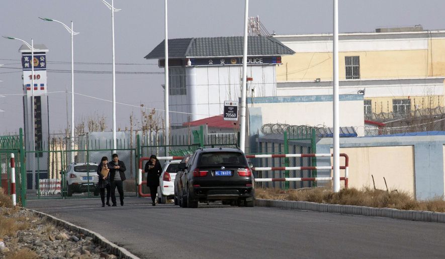 FILE - In this Dec. 3, 2018, file photo, people walk by a police station by the front gate of the Artux City Vocational Skills Education Training Service Center in Artux in western China&#39;s Xinjiang region. A coalition of human-rights groups has met with the International Olympic Committee over calls to pull the 2022 Winter Olympics out of Beijing. (AP Photo/Ng Han Guan, File)