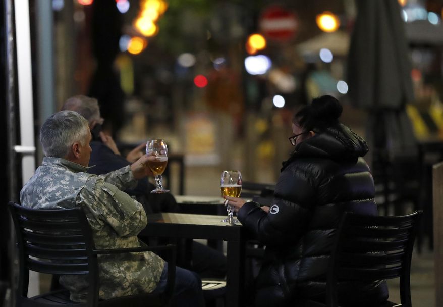 People drink a beer outside a restaurant in Liverpool, England, Wednesday, Oct. 14, 2020. As the first area in England slapped with strict new restrictions to curb the resurgent coronavirus that have shuttered pubs and imperiled thousands of jobs, Liverpool again feels it's being punished by policies made in Britain's capital, 180 miles (290 kilometers) to the south. (AP Photo/Frank Augstein)