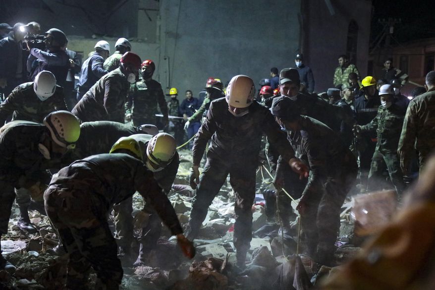 Soldiers and firefighters search for survivors in a residential area that was hit by rocket fire overnight by Armenian forces, early Saturday, Oct. 17, 2020, in Gyanga, Azerbaijan&#39;s second largest city, near the border with Armenia. (AP Photo/Aziz Karimov)