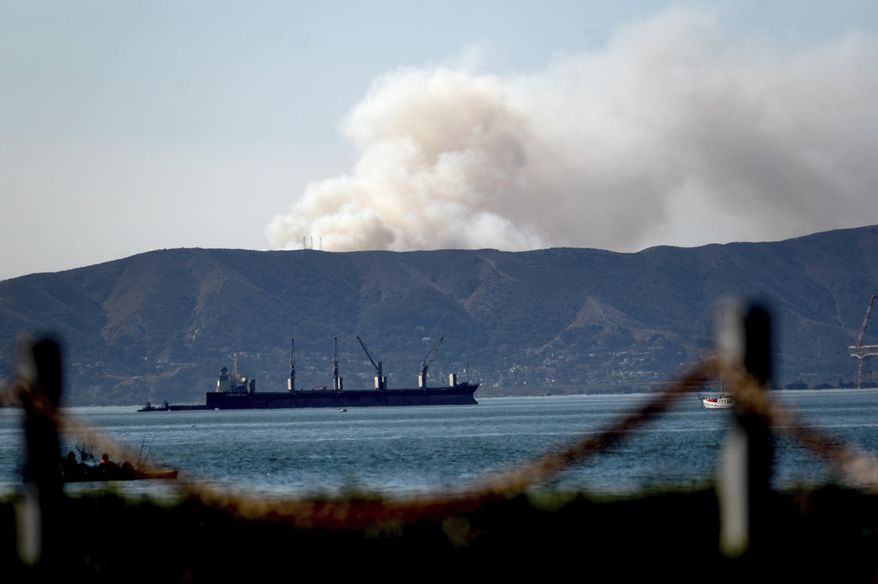 Seen from Alameda, Calif., a grass fire burns in South San Francisco on Friday, Oct. 16, 2020. Portions of Northern California remain under red flag fire warnings due to high temperatures and dry winds. (AP Photo/Noah Berger)