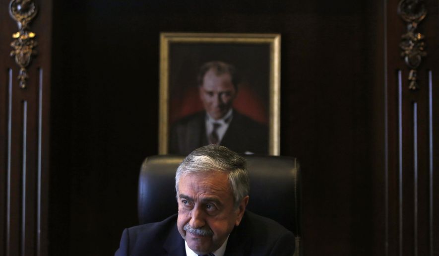 FILE - In this Monday, April 4, 2016 file photo, Turkish Cypriot leader Mustafa Akinci is seen at his office in front of the portrait of the Turkish Republic founder Kemal Ataturk, during an interview for the Associated Press in the Turkish breakaway north part of the divided capital Nicosia in this ethnically Mediterranean island of Cyprus. Turkish Cypriots vote on Sunday Oct. 18, 2020 in a leadership runoff that could decide if they want to retain more control over their own affairs or steer even closer to an increasingly domineering Turkey. (AP Photo/Petros Karadjias, File)