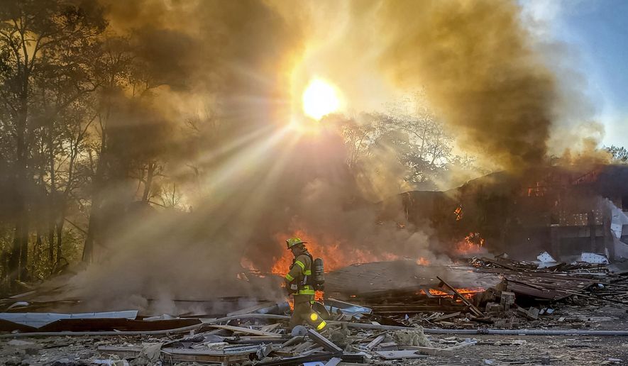 A firefighter walks through the burning rubble of a shopping center after an explosion in Harrisonburg, Va., Saturday, Oct. 17, 2020. Three people were transported for injuries from the blast. The cause of the explosion has not been released yet. (Ian Munro /Daily News-Record via AP)