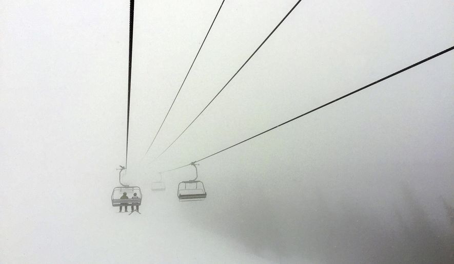 FILE - In this March 24, 2019 file photo, skiers ride a chair lift into a bank of fog at Colorado&#39;s Beaver Creek Resort. Resorts are trying to figure out how to safely reopen and are asking guests to embrace a new normal while skiing and snowboarding amid a pandemic. That could mean wearing face masks, standing 6 feet apart in lift lines, no dine-in service, riding lifts only with your group and no large gatherings for an apres drink. (AP Photo/Thomas Peipert, File)