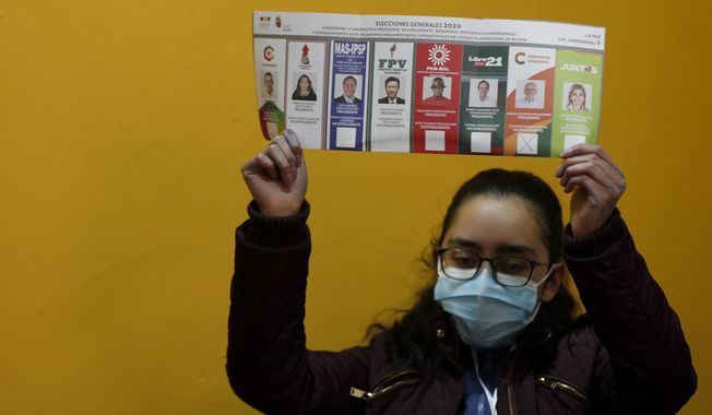 An electoral official holds a ballot as they count votes after polls closed for general elections in La Paz, Bolivia, Sunday, Oct. 18, 2020. (AP Photo/Juan Karita)