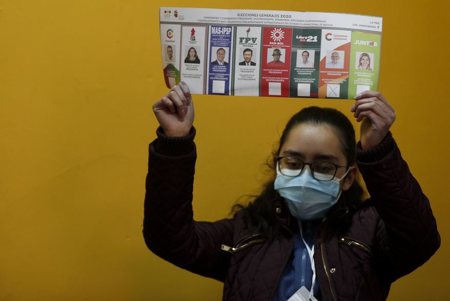 An electoral official holds a ballot as they count votes after polls closed for general elections in La Paz, Bolivia, Sunday, Oct. 18, 2020. (AP Photo/Juan Karita)