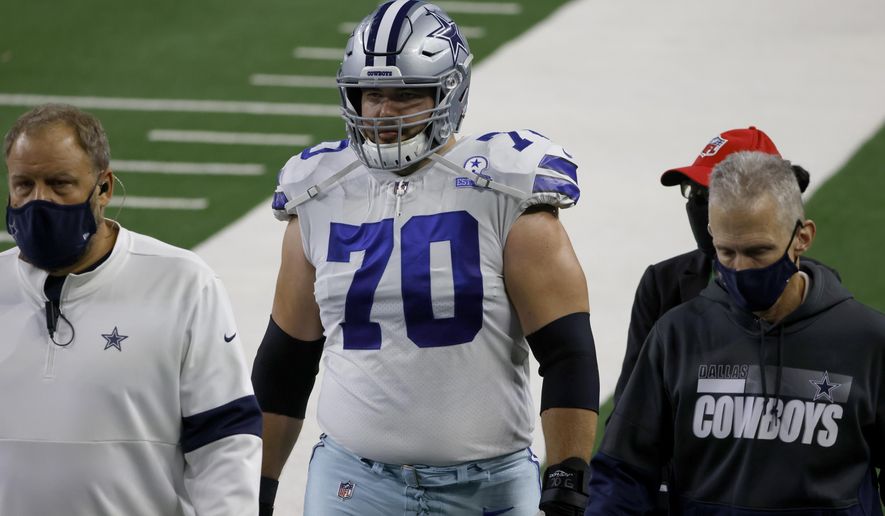 Dallas Cowboys guard Zack Martin (70) is escorted off the field after suffering an unknown injury in the first half of an NFL football game against the Arizona Cardinals in Arlington, Texas, Monday, Oct. 19, 2020. (AP Photo/Ron Jenkins)
