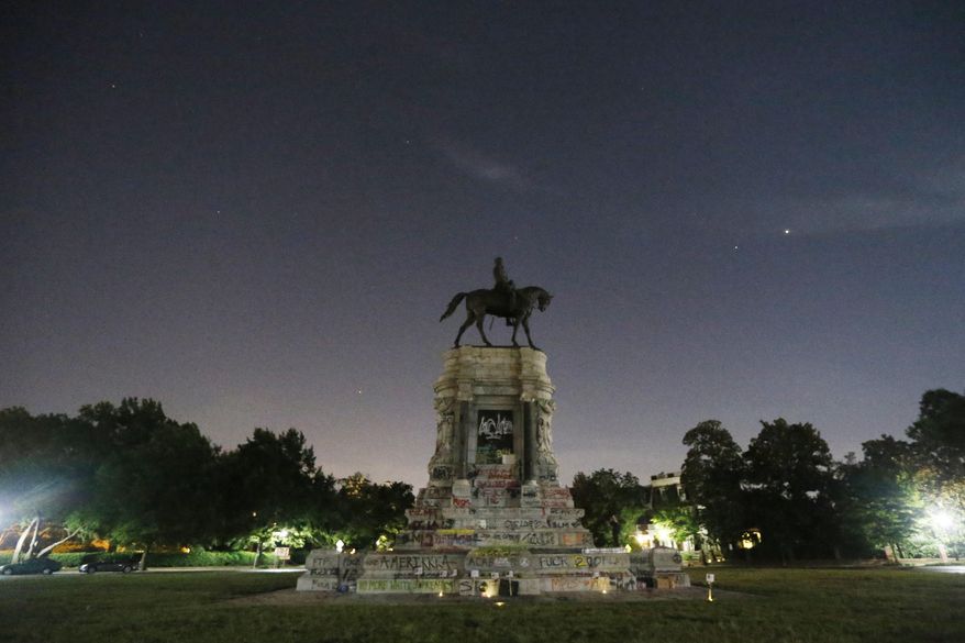 The moon and street lights illuminate the statue of Confederate General Robert E. Lee on Monument Avenue Friday June. 5, 2020, in Richmond, Va. A lawsuit seeking to prevent Virginia Gov. Ralph Northam from removing the statue is scheduled to go to trial Monday, Oct. 19, 2020. (AP Photo/Steve Helber)