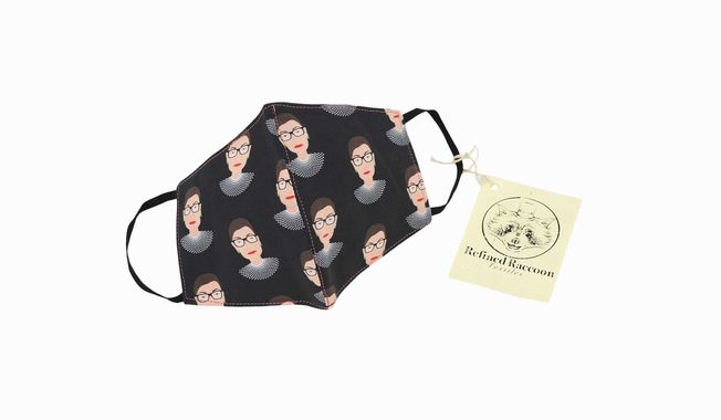 This product image released by Refined Raccoon Textiles shows a 100% cotton face mask featuring a repeating design of the late Supreme Court justice Ruth Bader Ginsburg&#x27;s head against a black background. Ten percent of each purchase will be donated to the American Cancer Society in Ginsburg&#x27;s honor. (Refined Raccoon Textiles via AP)