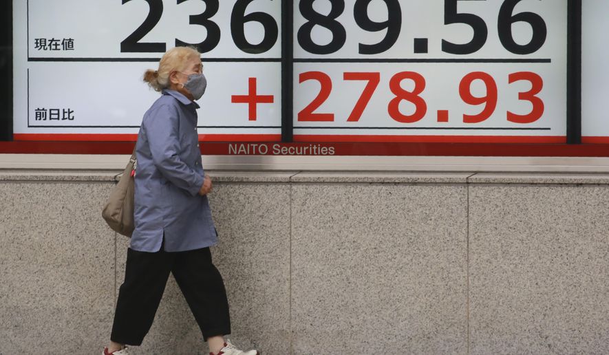 A woman walks by an electronic stock board of a securities firm in Tokyo, Monday, Oct. 19, 2020. Shares advanced in Asia on Monday after China reported its economy grew at a 4.9% annual pace in the last quarter, with consumer spending and industrial production rising to pre-pandemic levels. (AP Photo/Koji Sasahara)